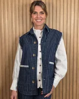 Chaleco de denim azul oscuro con diseño a rayas verticales, cierre frontal con botones y bolsillos frontales con costuras decorativas en contraste.