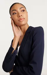 Blazer azul marino de corte clásico con solapa de muesca, cierre frontal con un botón y bolsillos con solapa.