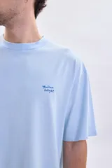 Remera de manga corta con corte oversize, color celeste, con estampa en la espalda que dice 'Italian Delight' en color azul.