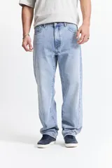Jean baggy color azul claro, de tiro medio, con corte amplio en piernas y cadera, y pasacinto.