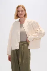 Chaqueta color crema de algodón con cuello mao, cierre frontal con botones, bolsillos laterales y mangas largas.