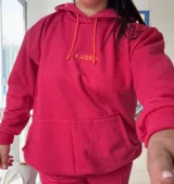 Canguro deportivo de tela suave con logo bordado, diseño holgado y mangas largas.