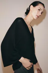 Top fluido de punto liso en color blanco, con escote en V pronunciado y mangas cortas amplias.