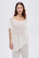 Poncho de punto asimétrico en color marfil, con escote bote amplio y diseño holgado de caída fluida.