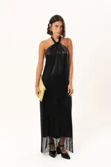 Vestido midi de satén color negro, con escote halter cruzado y ruedo terminado en flecos largos.
