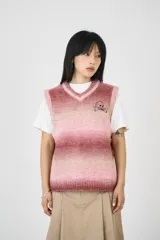 Chaleco de punto con escote en V y diseño degradado en tonos rosados. Presenta un logo de calavera bordado en el pecho.