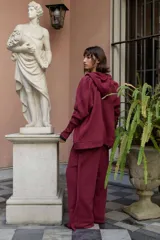 Campera deportiva oversize color bordó con capucha, cierre metálico frontal y mangas raglán de volumen pronunciado. Cuenta con puños largos de rib elástico y cordones regulables a tono con terminaciones metálicas.