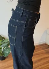 Pantalon de jean azul oscuro con costuras en contraste, corte wide leg y ruedo con doblez ancho en tono denim claro.