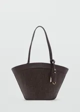 Bolso tipo shopper de tamaño mediano confeccionado en tejido de fibra natural con detalles en poliuretano. Cuenta con dos asas largas para llevar al hombro, cierre de cremallera superior, bolsillo interior y un charm colgante decorativo con herrajes dorados.