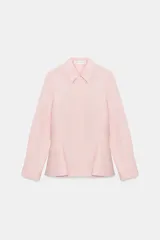 Camisa de popelín de algodón con cuello solapa, manga larga con puños y bajo con diseño peplum. Presenta cierre frontal con botones ocultos por solapa.