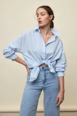Camisa celeste de corte oversize, con mangas largas, cuello camisero y cierre frontal de botones.