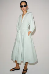 Vestido midi camisero de algodón color verde menta, con cuello camisero, manga abullonada por debajo del codo, cierre frontal con botones y lazo ajustable en la cintura.