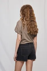 Falda short de denim con diseño a rayas verticales y costuras en contraste. Presenta frente asimétrico con efecto de falda, tiro medio, bolsillos delanteros y cierre con botón.