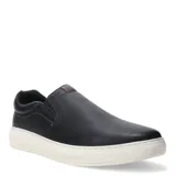 Zapatos tipo slip-on de cuero negro con suela de goma blanca. Presenta paneles elásticos laterales para facilitar el calce y un detalle de marca en la lengüeta.