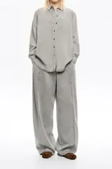 Pantalón jean ancho gris, de tiro bajo, confeccionado en mezcla de lyocell y algodón, con bolsillos delanteros y pespuntes decorativos.