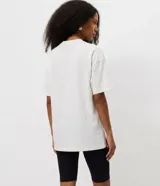 Remera de corte regular y manga corta, confeccionada en algodón. Presenta cuello redondo y una estampa frontal que simula un vestido de breteles finos con detalles de encaje.