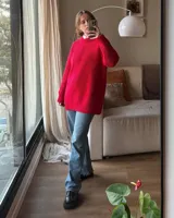 Buzo unisex de tejido de punto grueso en lana merino, color rojo, con cuello redondo y diseño de calce relajado. Presenta un detalle bordado a mano en contraste en la manga.