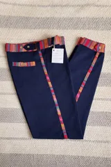 Bombacha de campo azul marino, de corte recto y tiro medio, confeccionada en acrocel de algodón. Presenta detalles de tela tejida multicolor en la cintura, pasadores, ribetes de los bolsillos y laterales de las piernas.