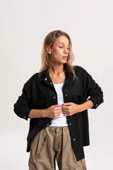 Sobrecamisa oversize de textura simil gamuza en color negro, con cierre frontal de botones metálicos a presión, cuello clásico y bolsillos frontales.
