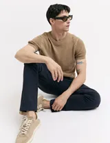 Pantalón de vestir marrón, de corte recto, con bolsillos laterales y traseros. Se ajusta a la cintura con cinturón de cuero marrón.