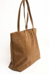 Bolso tipo tote bag de tamaño maxi color suela, confeccionado en material sintético con textura efecto cuero gastado. Cuenta con doble asa de hombro y placa metálica con la inscripción de la marca en la parte frontal.