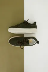 Zapatillas de gamuza verde oliva con cordones marrones y suela de goma color crema.