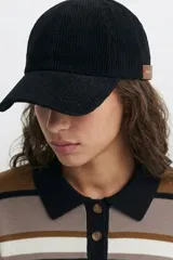 Gorro tipo cap de pana color negro, con textura acanalada y etiqueta lateral de cuero sintético.