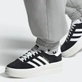 Championes Adidas Gazelle Bold negros con plataforma blanca y las tres tiras características en blanco.