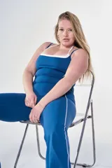 Conjunto deportivo de dos piezas en color azul prusia con detalles en blanco. Incluye un top con breteles finos y escote cuadrado con ribete blanco, y un pantalón tipo calza con franjas laterales blancas.