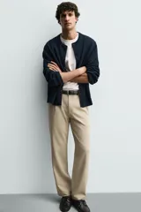 Pantalón de corte recto confeccionado en tejido elástico, con cintura elástica, pliegues frontales, bolsillos laterales y bolsillos traseros de vivo con botón.