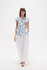 Blusa de rayón con estampado floral en tonos azules y celestes sobre fondo blanco. Presenta cuello en V, botones frontales y mangas cortas con frunces en los hombros.