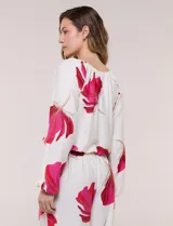 Conjunto de dos piezas de crep compuesto por una blusa holgada con escote en V y mangas largas abullonadas, y un pantalón palazzo tiro alto con pretina elástica. Presenta un estampado floral en tonos rosados sobre base blanca.