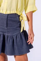 Falda corta de jean azul con volados en el ruedo y costuras en hilo blanco.