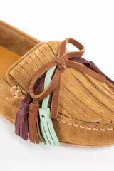 Mocasin de gamuza color camel, con detalle de flecos decorativos en la parte frontal en tonos marrón, violeta y verde agua.