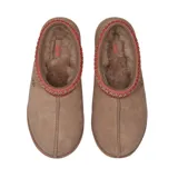 Pantuflas UGG modelo Tasman II, confeccionadas en gamuza color tostado. Presentan un diseño sin cordones con detalle de trenza decorativa en el borde superior y suela de goma resistente.