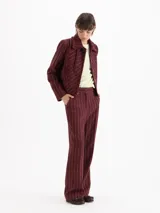 Pantalon de sastreria color bordeaux con diseño de rayas finas verticales blancas, de tiro alto y pierna recta.
