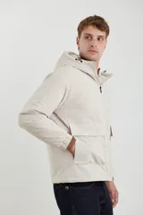 Campera color beige con capucha, cierre frontal y bolsillos con solapa.