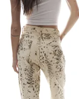 Pantalón de jean color crema con estampado abstracto en tonos marrones, de corte recto y tiro alto.