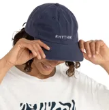 Gorra de visera curva color azul marino, con el logo de la marca 'RHYTHM' bordado en letras blancas en la parte frontal.