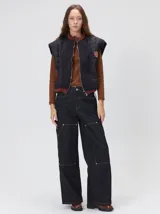 Chaleco de corte cuadrado con diseño bicolor en tonos terracota y crema. Presenta cierre frontal metalizado, parches de nylon en el pecho, interior forrado en corderito y cordón ajustable en el ruedo.