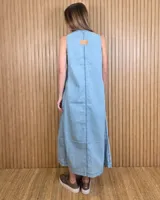 Vestido largo de denim celeste, sin mangas, con escote en V, corte amplio, bolsillos laterales y tajos pronunciados en la parte inferior con detalles de pespuntes.