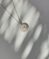 Collar plateado con dije redondo texturizado.