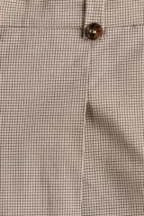 Pantalón sastrero de corte cropped y tiro alto, con piernas amplias y pliegues frontales. Presenta cierre con botón y trabillas en la cintura, en un tono beige con estampado de microcuadros.