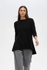 Sweater negro de punto acanalado, con cuello redondo a la base, manga larga y corte holgado con aberturas laterales.