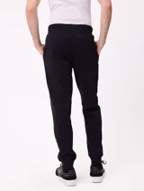 Babucha jogger color gris oscuro, con cintura elástica ajustable con cordón, bolsillos laterales y puños elásticos en los tobillos. Presenta un logo estampado en el muslo izquierdo.