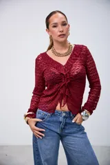 Blusa de encaje color bordó, de manga larga, con escote en V y volados en el borde delantero.