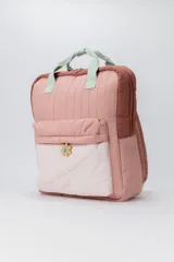 Mochila acolchada con diseño capitoné en tonos rosados y beige, con asas de mano color verde menta. Presenta un bolsillo frontal con un dije de flor sonriente.