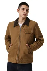 Campera de canvas color marrón con cuello de pana en contraste, cierre frontal completo, bolsillo en el pecho con solapa y bolsillos laterales inclinados.