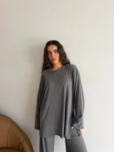 Conjunto oversize de dos piezas en tejido acanalado color beige, compuesto por una remera de manga larga con aberturas laterales y un pantalón largo de corte recto y holgado.