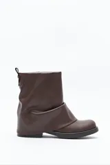 Bota de caña baja color marrón, con diseño minimalista y efecto fruncido. Presenta puntera redondeada, base baja y un sutil detalle metálico en la caña.